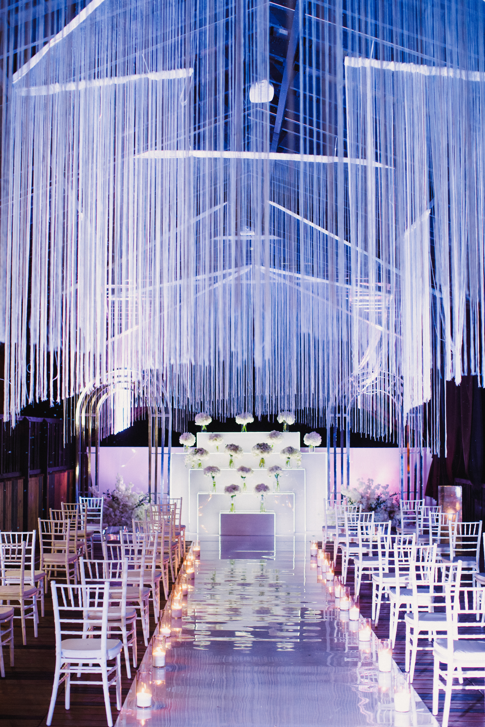 white chairs in wedding hall and wedding ceremony venue in white and violet and festoon shining